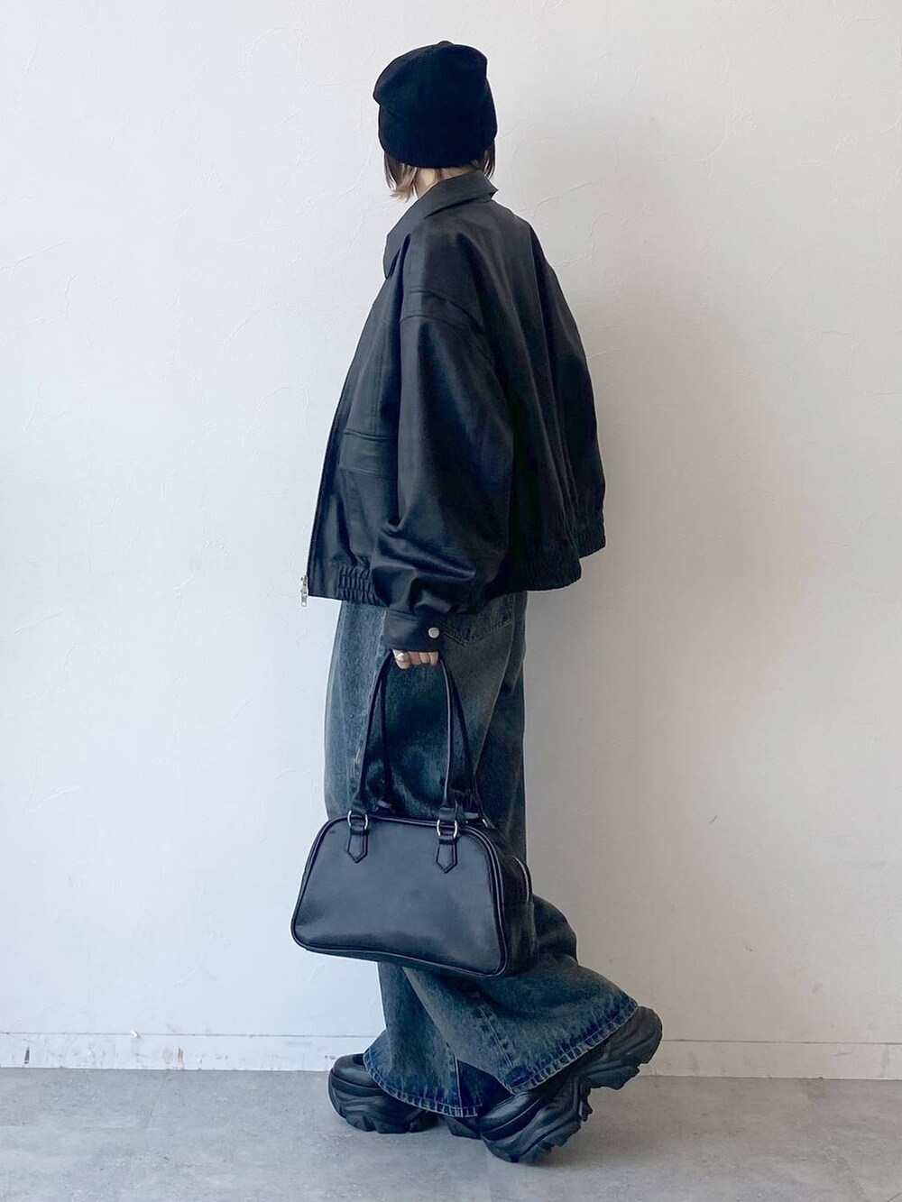 ブラック系のスニーカー、ブルー系のデニムパンツ、ブラック系のブルゾンを着用したレディースの夏コーディネートの4枚目の写真