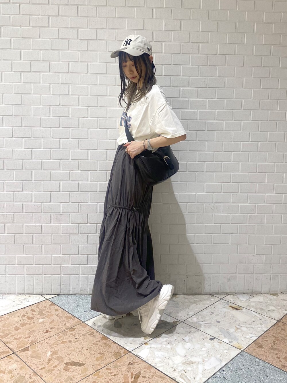 ホワイト系のスニーカー、ブラック系のショルダーバッグ、ベージュ系のTシャツ/カットソーを着用したレディースの夏コーディネートの2枚目の写真