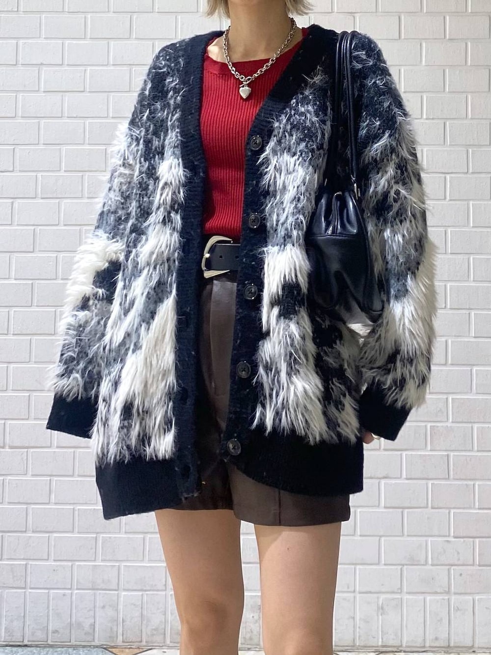 ブラウン系のブーツ、ブラック系のボストンバッグ、レッド系のニット/セーターを着用したレディースの秋コーディネートの8枚目の写真