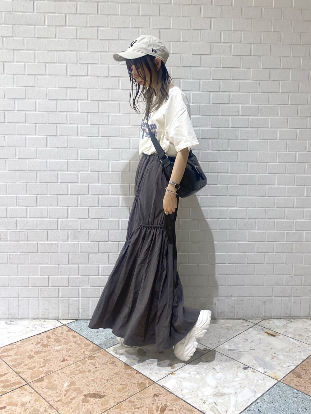 ホワイト系のスニーカー、ブラック系のショルダーバッグ、ベージュ系のTシャツ/カットソーを着用したレディースの夏コーディネートの3枚目の写真