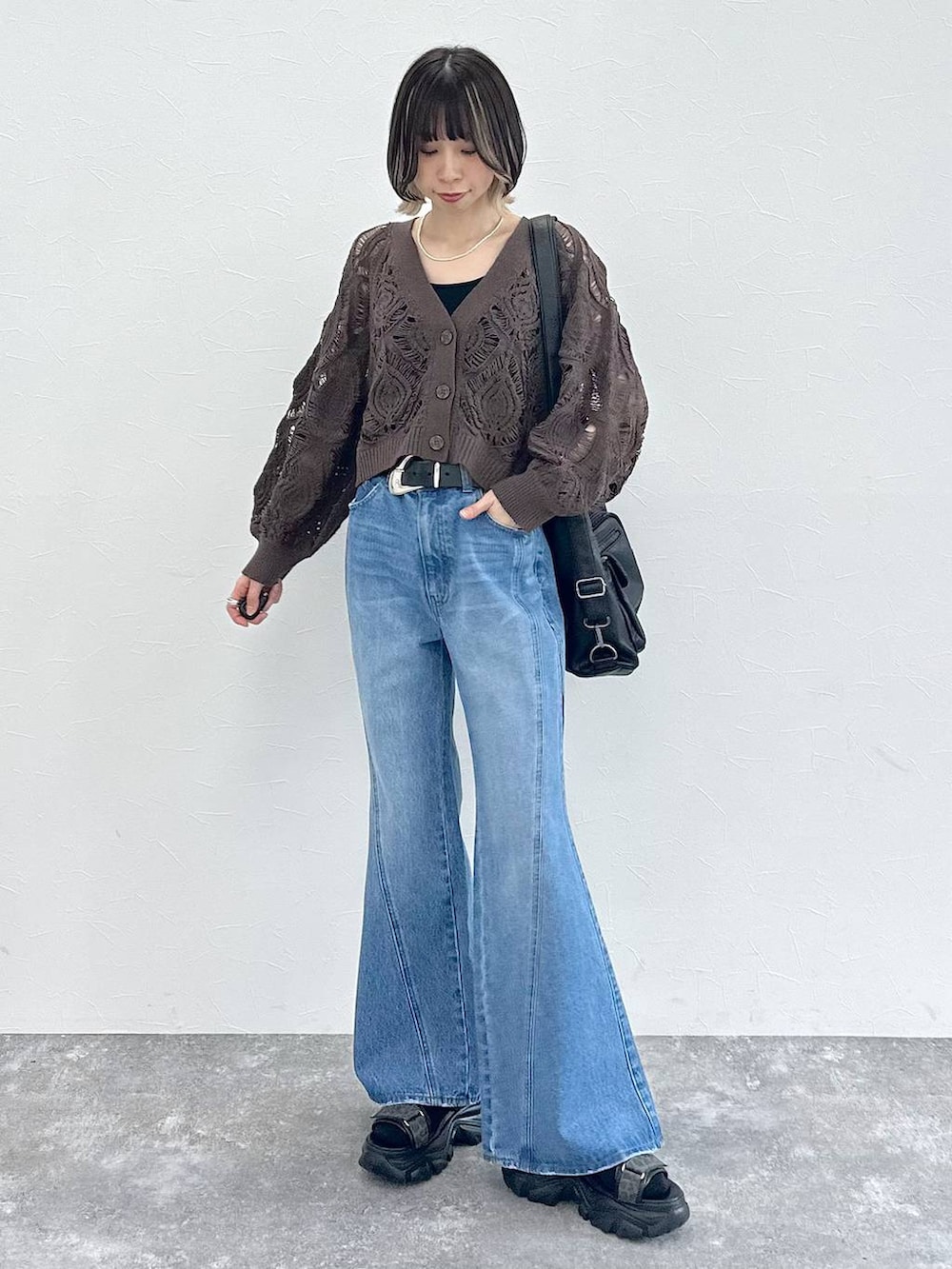 ブラック系のキャミソール、ブラウン系のカーディガン/ボレロ、ブルー系のデニムパンツを着用したレディースの春コーディネートの2枚目の写真