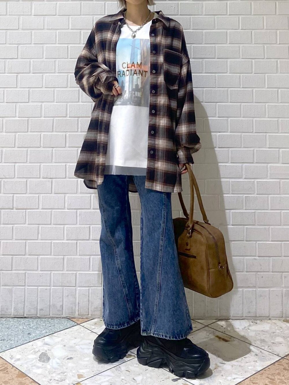 ブラック系のスニーカー、イエロー系のボストンバッグ、ブルー系のデニムパンツを着用したレディースの秋コーディネートの2枚目の写真