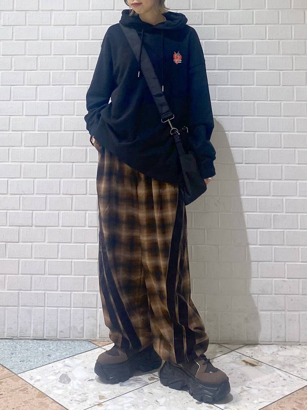 ブラウン系のブーツ、ブラック系のボストンバッグ、ブラック系のパーカーを着用したレディースの秋コーディネートの2枚目の写真