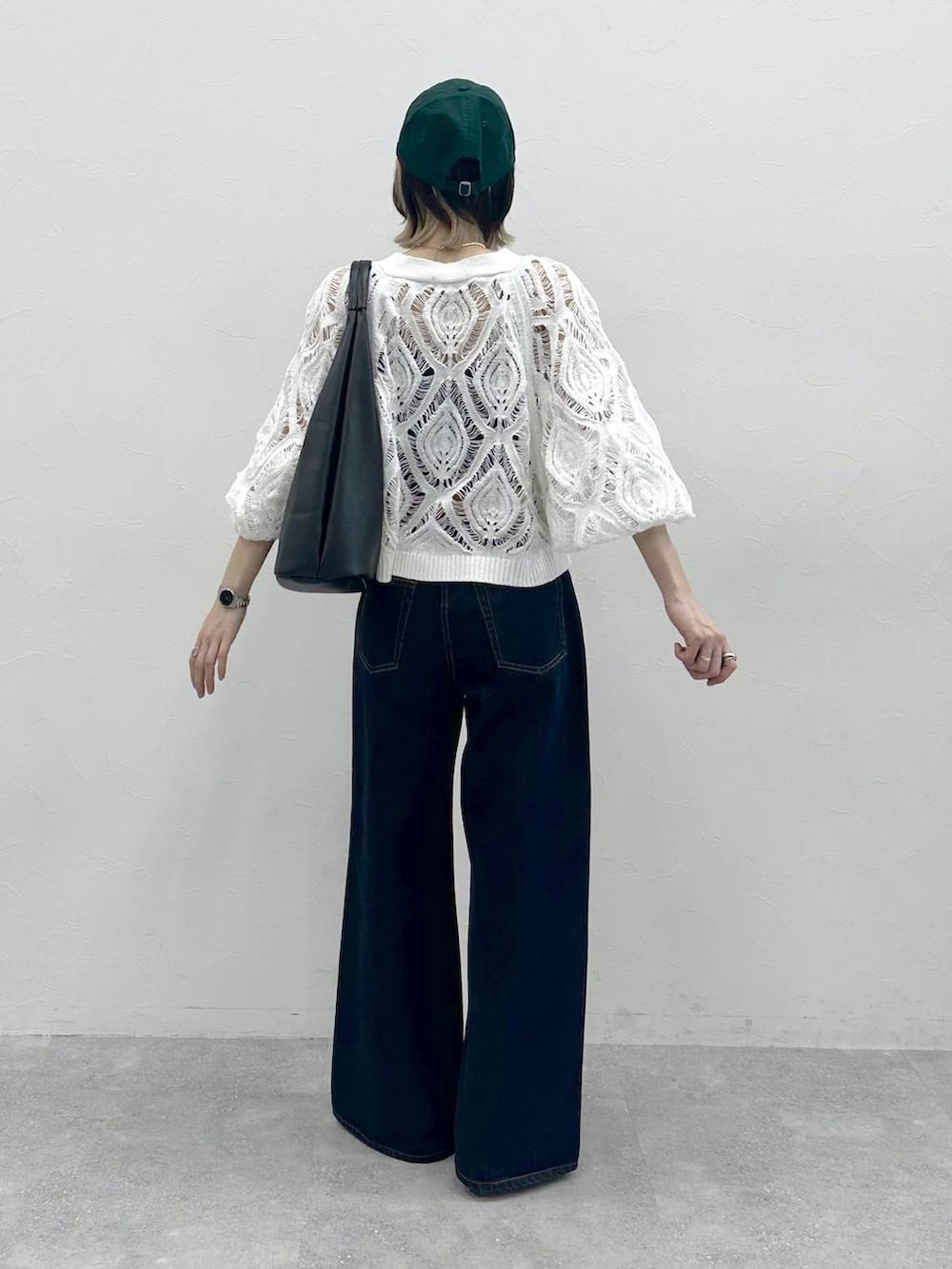 ブラック系のキャミソール、ホワイト系のカーディガン/ボレロ、ブルー系のスラックスを着用したレディースの春コーディネートの6枚目の写真