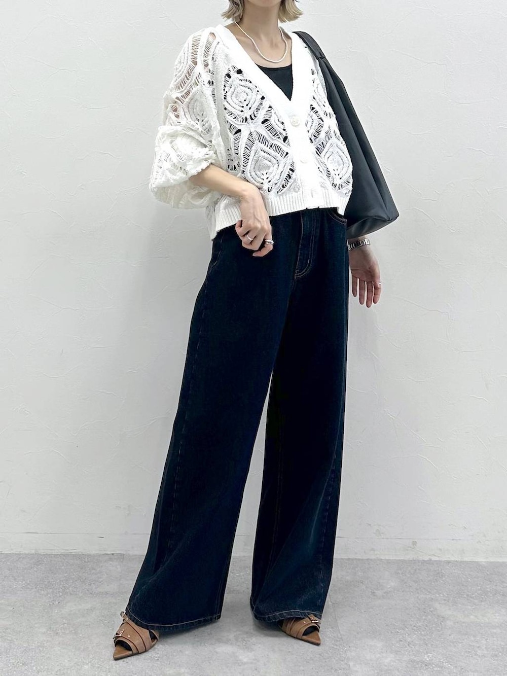 ブラック系のキャミソール、ホワイト系のカーディガン/ボレロ、ブルー系のスラックスを着用したレディースの春コーディネートの3枚目の写真