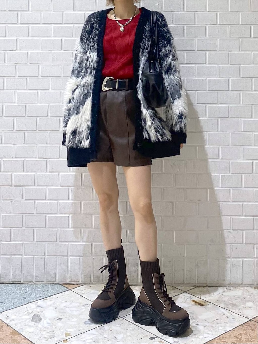 ブラウン系のブーツ、ブラック系のボストンバッグ、レッド系のニット/セーターを着用したレディースの秋コーディネートの2枚目の写真