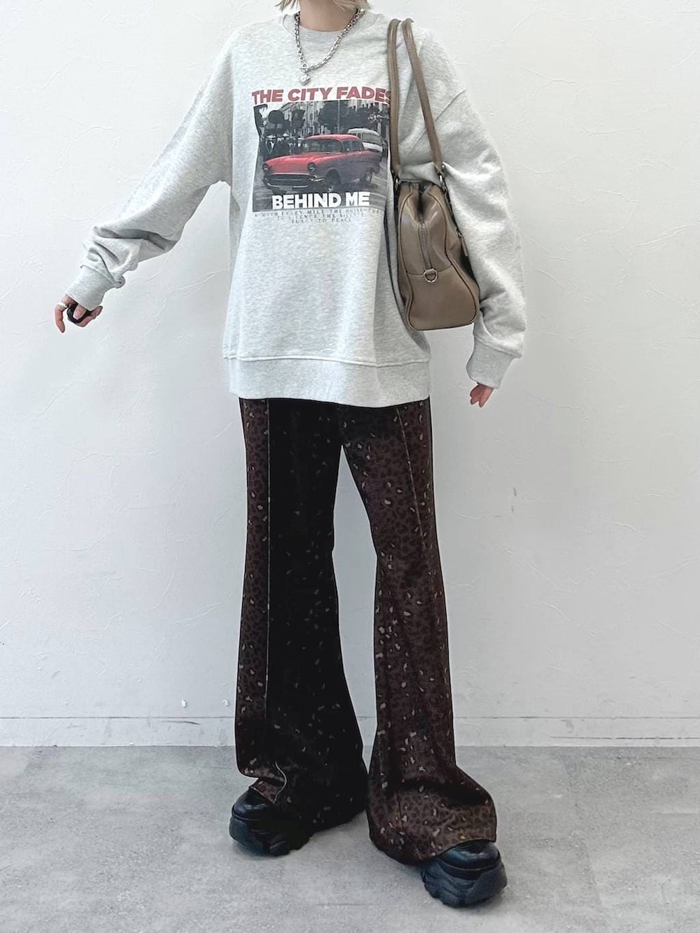 ブラック系のブーツ、ベージュ系のボストンバッグ、グレー系のスウェットを着用したレディースの冬コーディネートの2枚目の写真