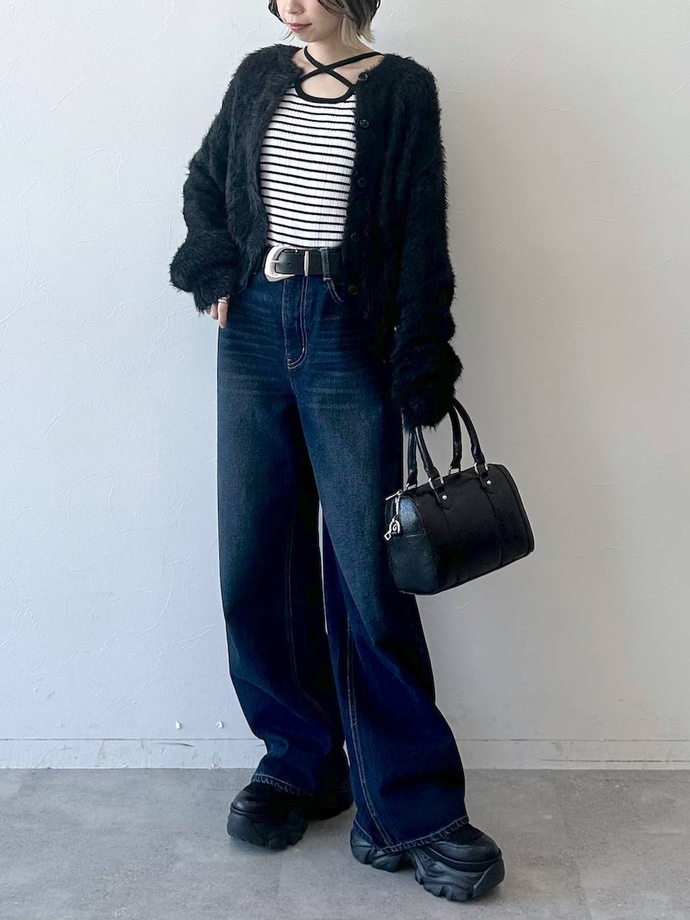 ブラック系のブーツ、ブルー系のスラックス、ブラック系のボストンバッグを着用したレディースの冬コーディネートの2枚目の写真