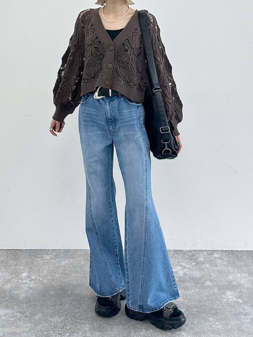 ブラック系のキャミソール、ブラウン系のカーディガン/ボレロ、ブルー系のデニムパンツを着用したレディースの春コーディネートの3枚目の写真