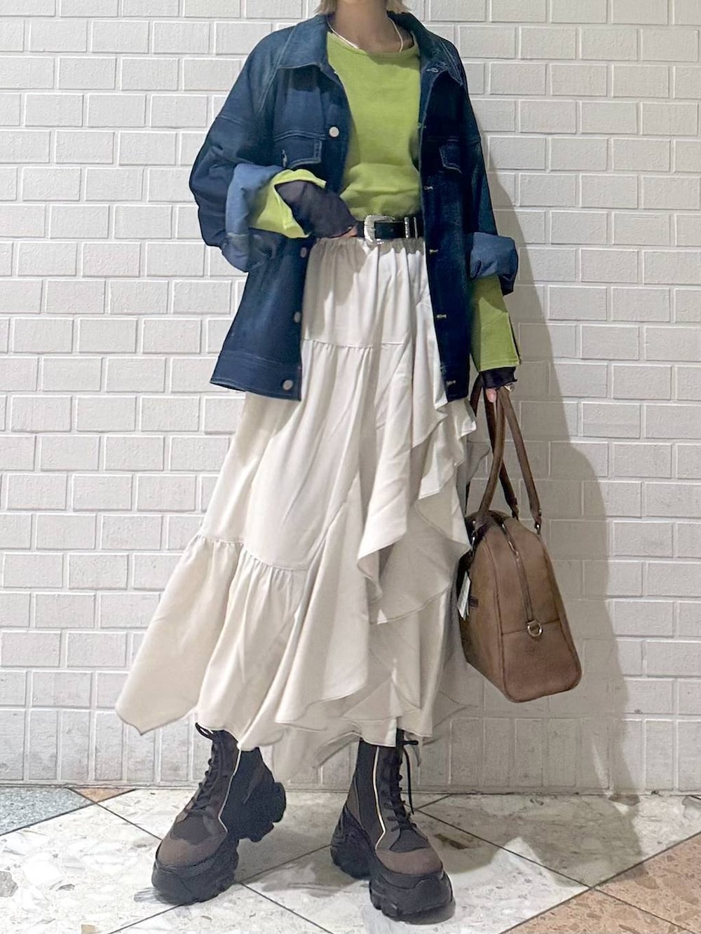 ブラウン系のブーツ、イエロー系のボストンバッグ、ベージュ系のスカートを着用したレディースの冬コーディネートの4枚目の写真