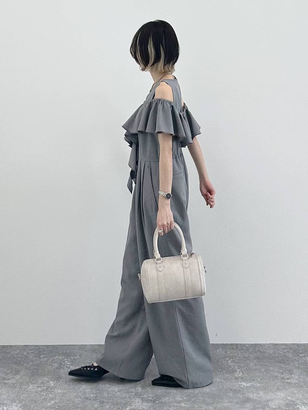 ホワイト系のボストンバッグ、ブラック系のサンダル、グレー系のサロペット/オーバーオールを着用したレディースの春コーディネートの6枚目の写真