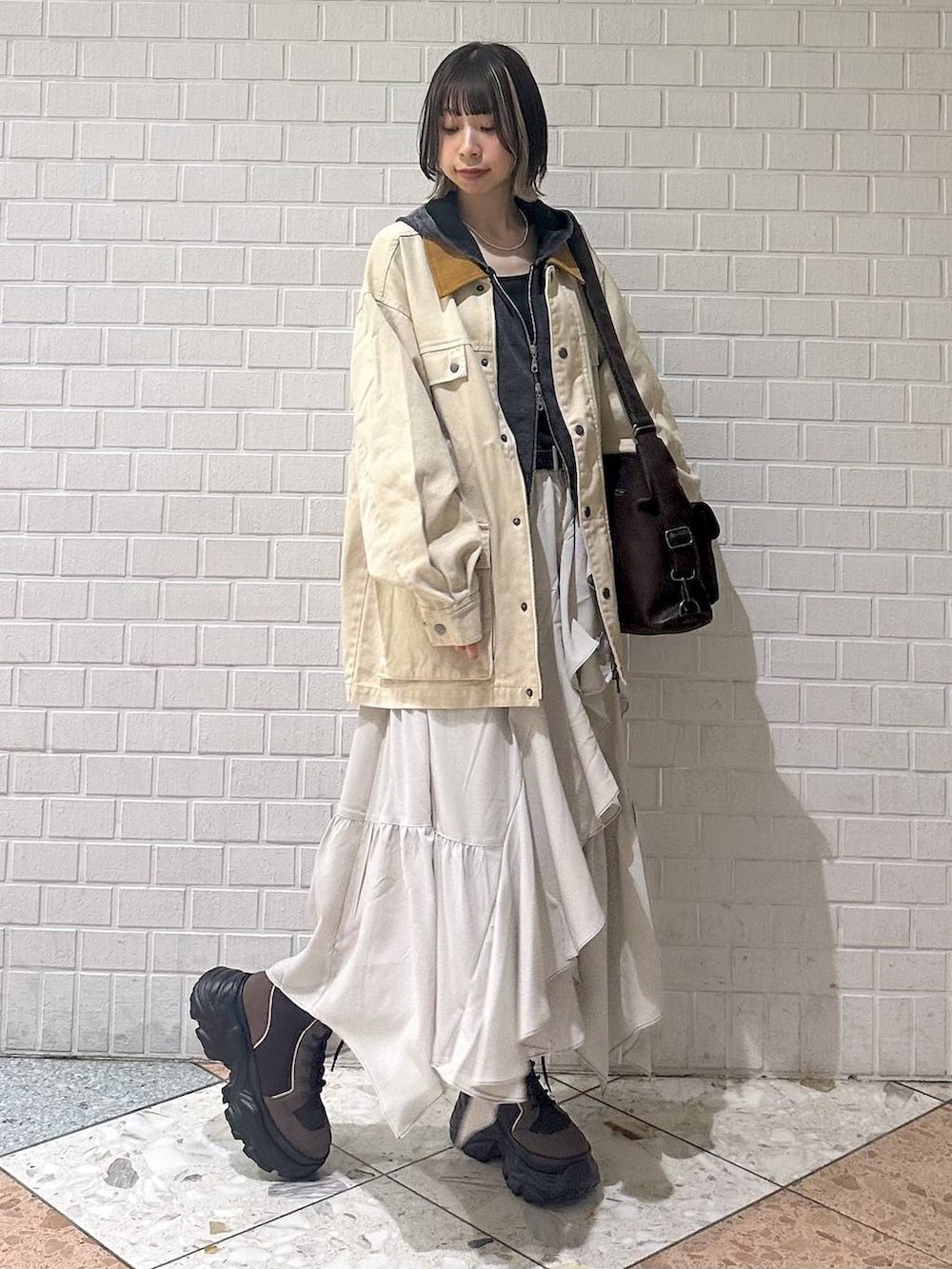 ブラウン系のブーツ、ブラック系のキャミソール、ベージュ系のスカートを着用したレディースの春コーディネートの9枚目の写真