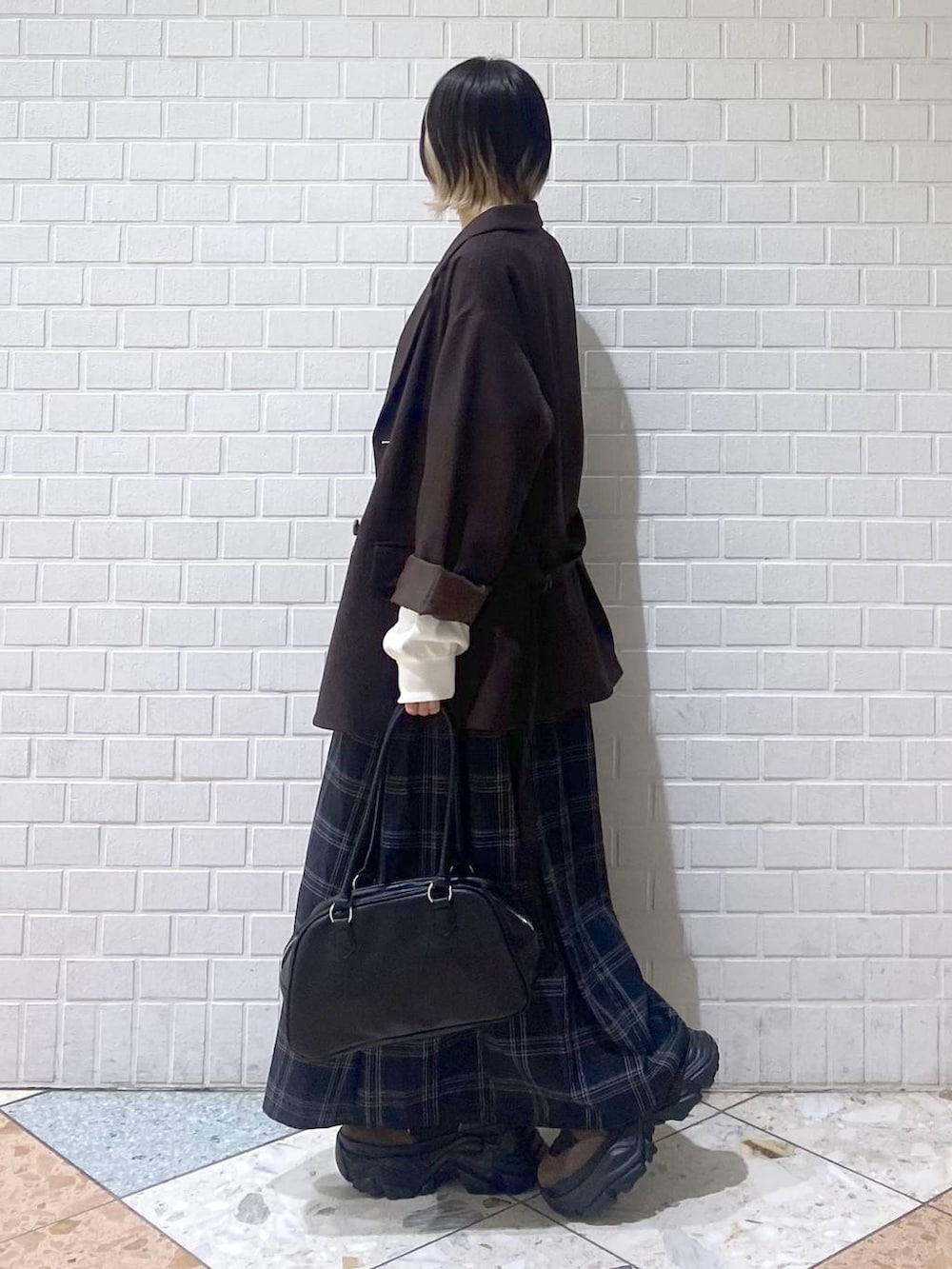 ブラウン系のブーツ、ブラック系のボストンバッグ、ホワイト系のニット/セーターを着用したレディースの秋コーディネートの4枚目の写真