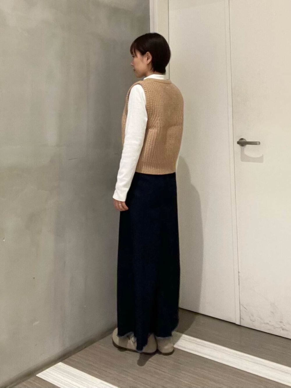 ベージュ系のベスト、ブルー系のスカート、ホワイト系のTシャツ/カットソーを着用したレディースの冬コーディネートの5枚目の写真