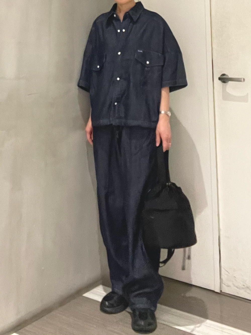 ブルー系のシャツ/ブラウス、ブルー系のデニムパンツ、ブラック系のショルダーバッグを着用したレディースの春コーディネートの2枚目の写真