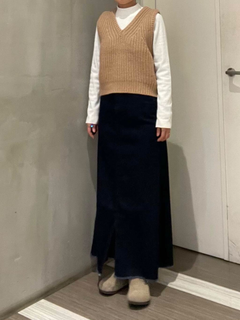 ベージュ系のベスト、ブルー系のスカート、ホワイト系のTシャツ/カットソーを着用したレディースの冬コーディネートの6枚目の写真