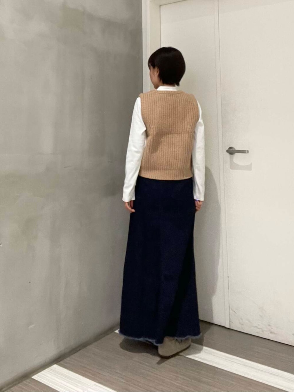 ベージュ系のベスト、ブルー系のスカート、ホワイト系のTシャツ/カットソーを着用したレディースの冬コーディネートの8枚目の写真