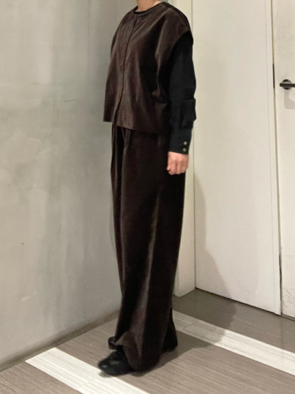 ブラック系のハンドバッグ、ブラック系のローファー、ブラウン系のベストを着用したレディースの秋コーディネートの3枚目の写真