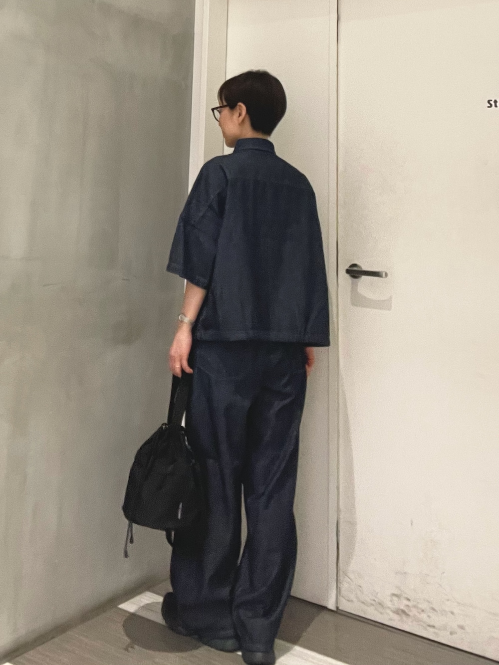 ブルー系のシャツ/ブラウス、ブルー系のデニムパンツ、ブラック系のショルダーバッグを着用したレディースの春コーディネートの3枚目の写真