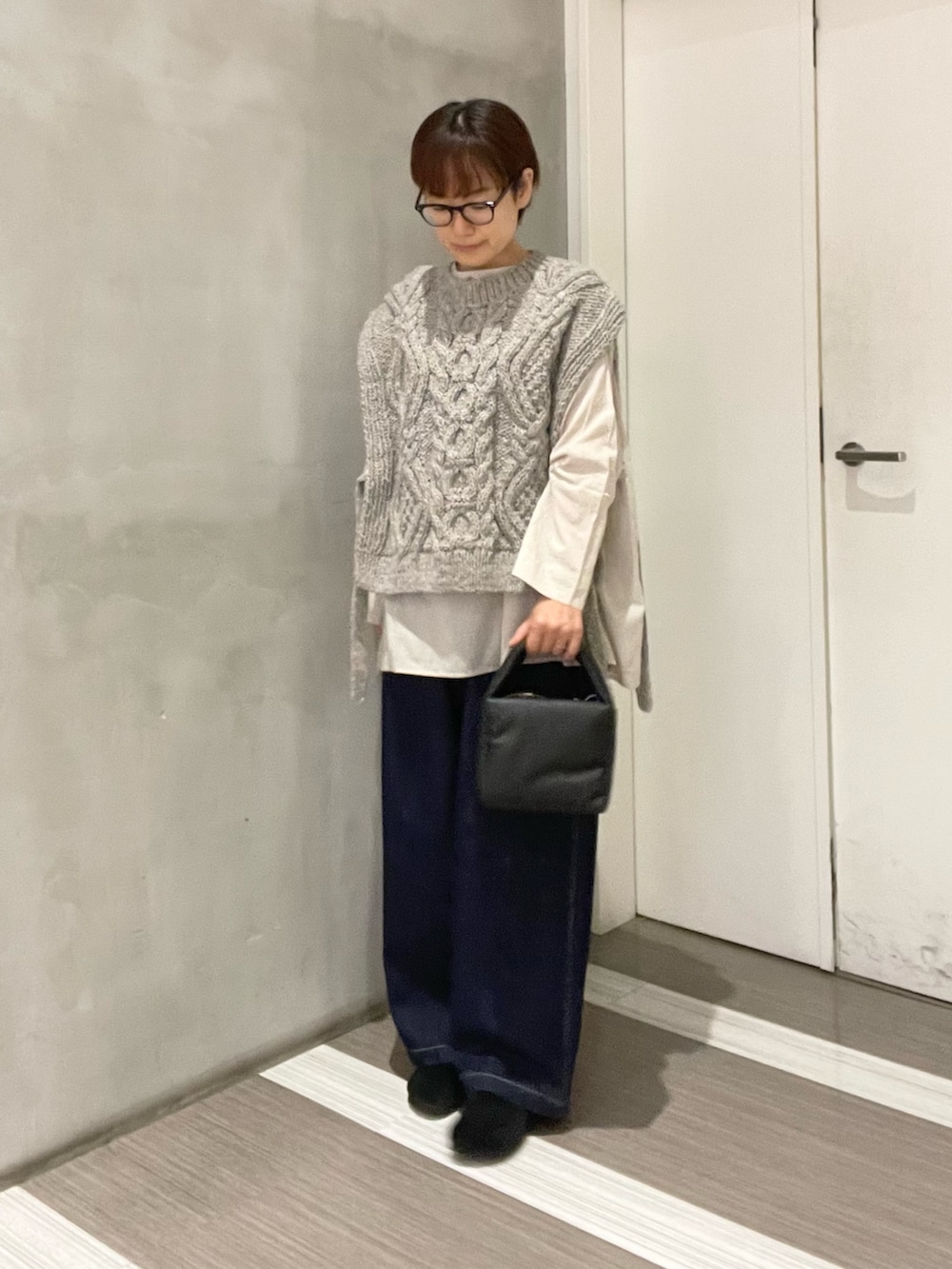 グレー系のニット/セーター、ベージュ系のシャツ/ブラウス、ブラック系のハンドバッグを着用したレディースの秋コーディネートの2枚目の写真