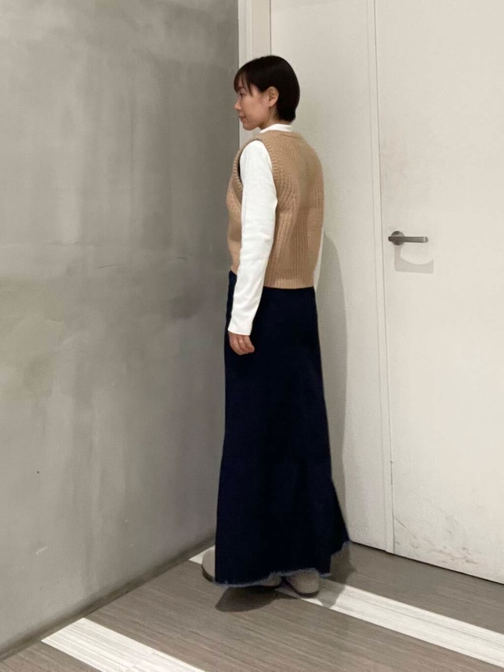 ベージュ系のベスト、ブルー系のスカート、ホワイト系のTシャツ/カットソーを着用したレディースの冬コーディネートの7枚目の写真