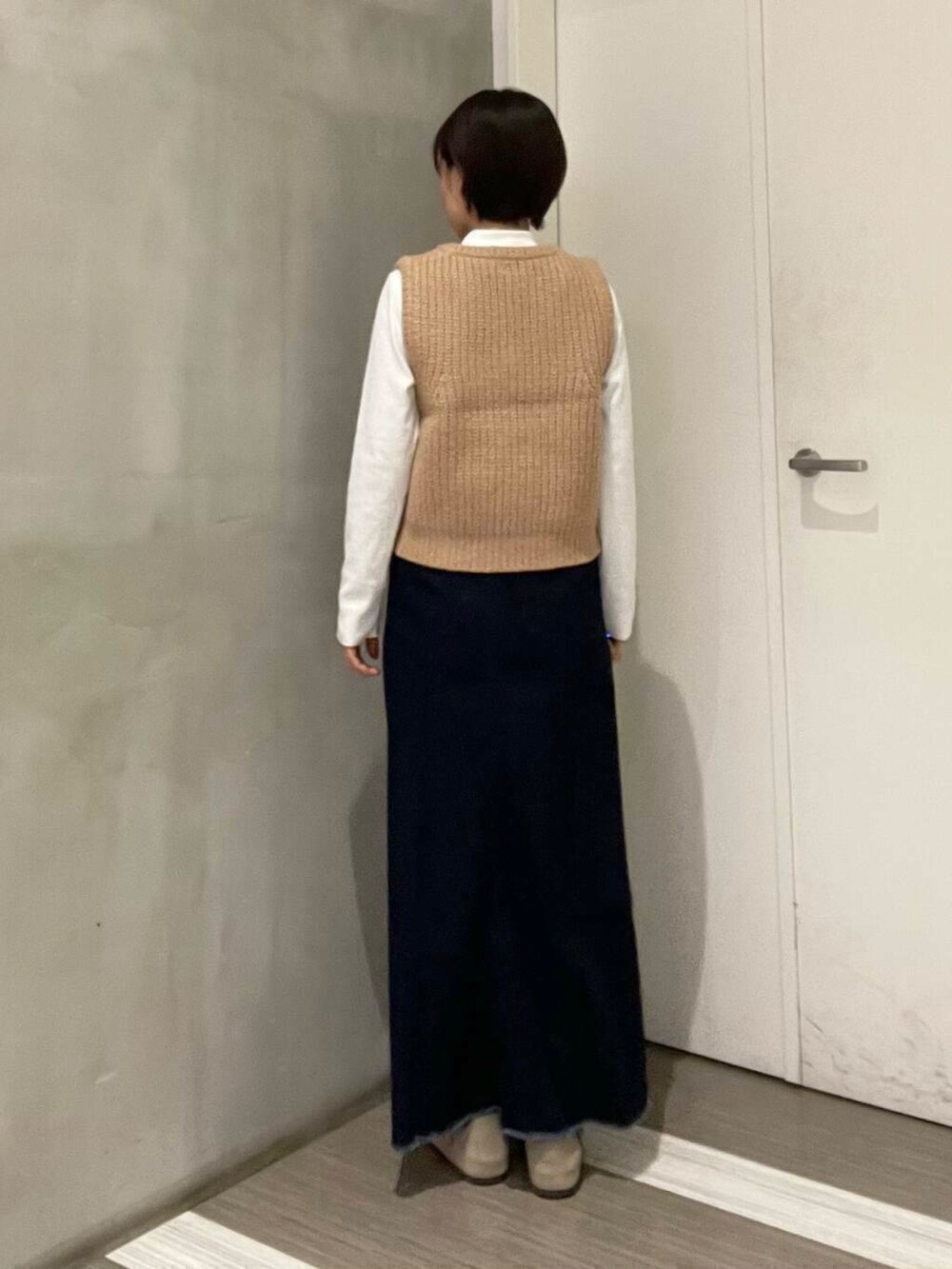 ベージュ系のベスト、ブルー系のスカート、ホワイト系のTシャツ/カットソーを着用したレディースの冬コーディネートの4枚目の写真