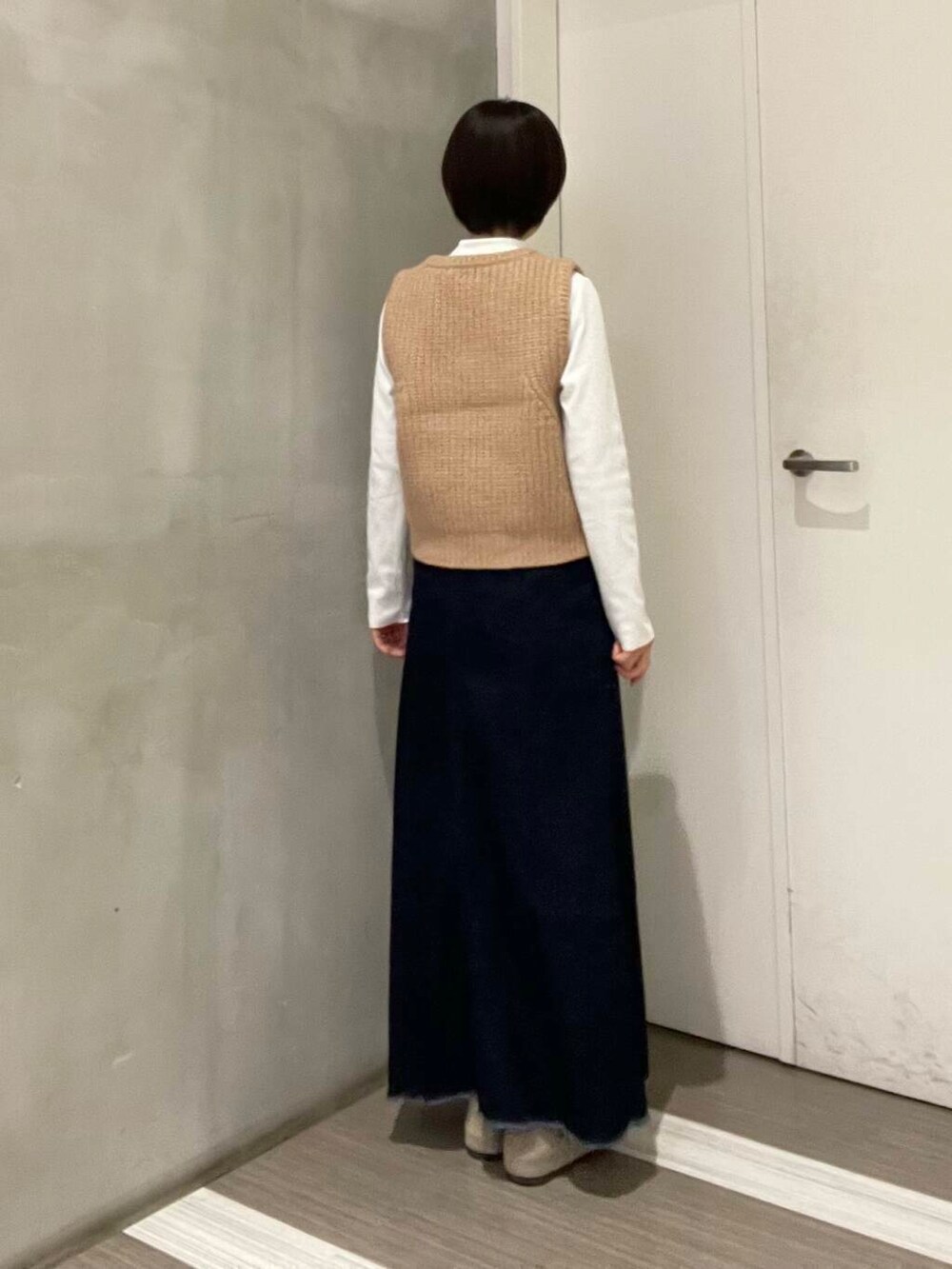 ベージュ系のベスト、ブルー系のスカート、ホワイト系のTシャツ/カットソーを着用したレディースの冬コーディネートの3枚目の写真