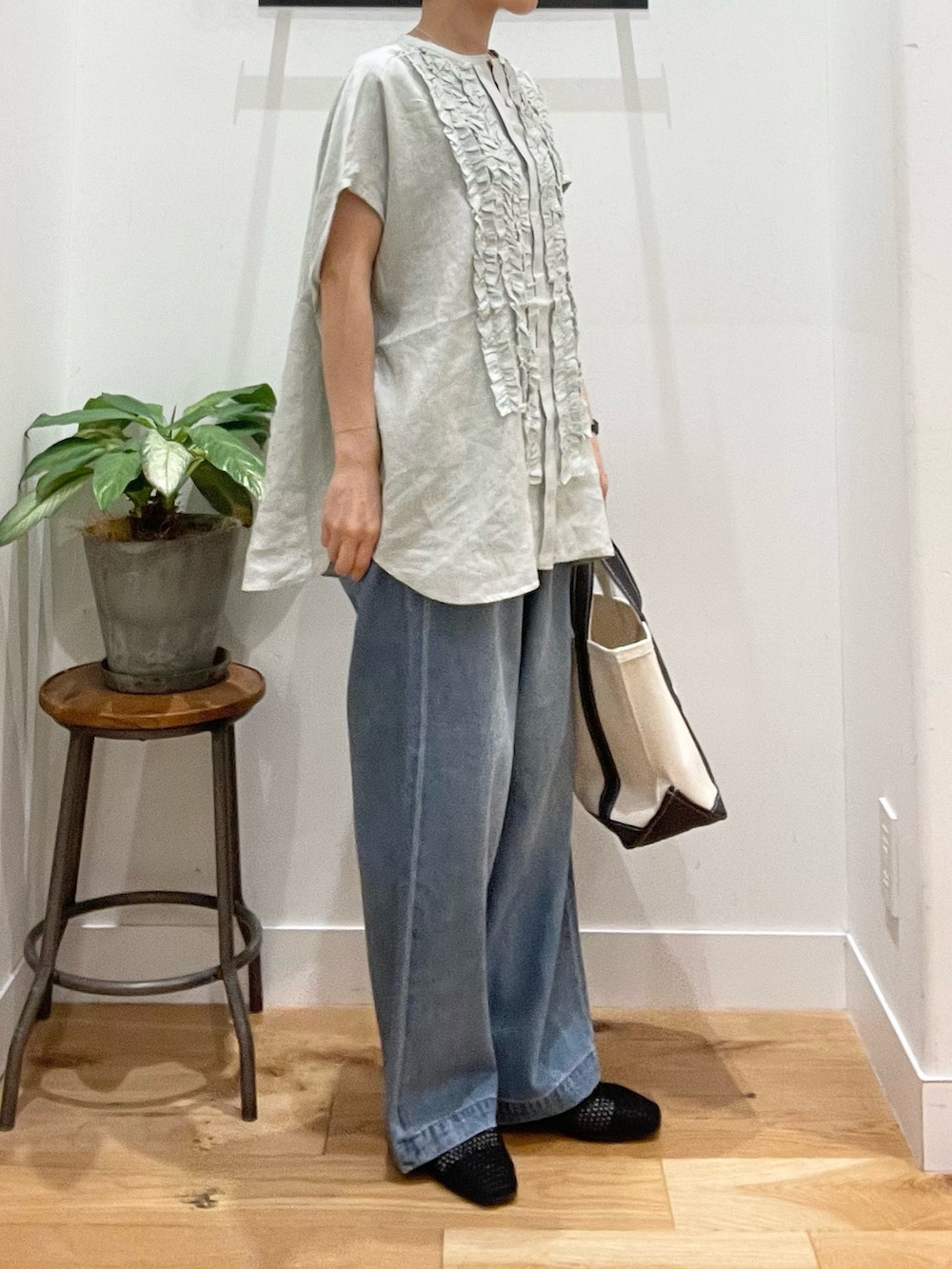 ブルー系のデニムパンツ、ホワイト系のトートバッグ、ブラック系のサンダルを着用したレディースの春コーディネートの3枚目の写真