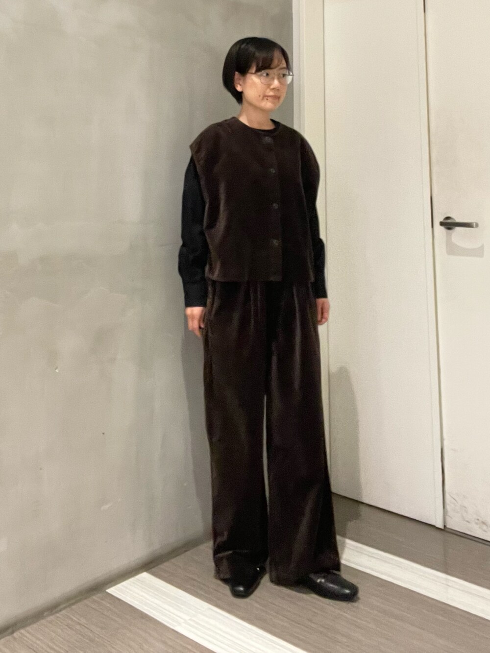 ブラック系のハンドバッグ、ブラック系のローファー、ブラウン系のベストを着用したレディースの秋コーディネートの5枚目の写真