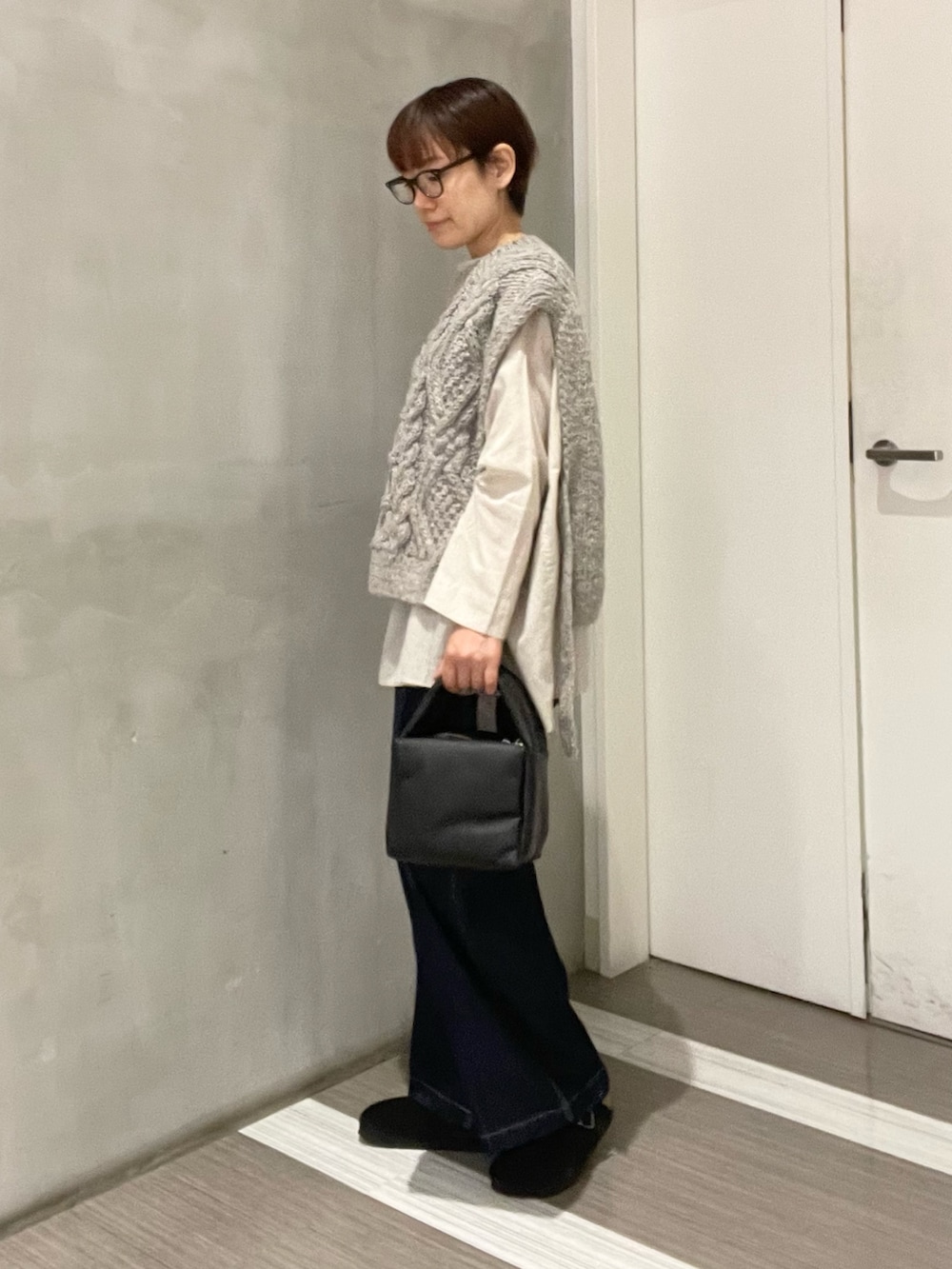 グレー系のニット/セーター、ベージュ系のシャツ/ブラウス、ブラック系のハンドバッグを着用したレディースの秋コーディネートの3枚目の写真