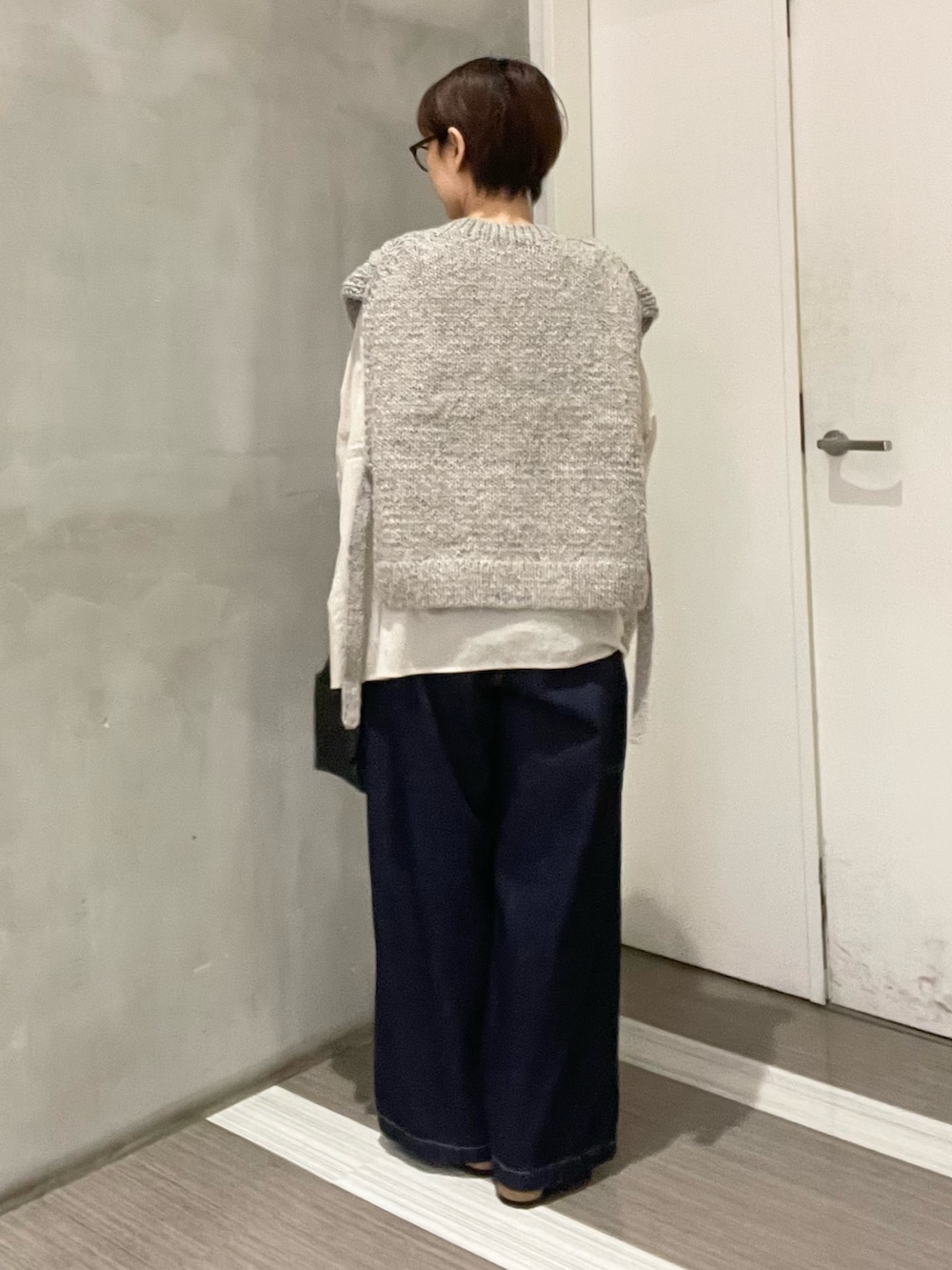 グレー系のニット/セーター、ベージュ系のシャツ/ブラウス、ブラック系のハンドバッグを着用したレディースの秋コーディネートの4枚目の写真