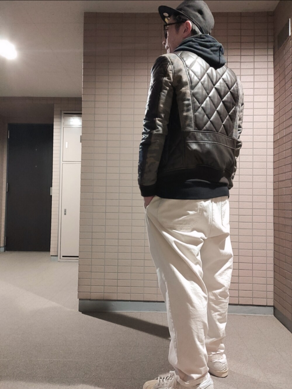 ブラウン系のブルゾン、ブラック系のパーカー、ホワイト系のスニーカーを着用したメンズの冬コーディネートの2枚目の写真