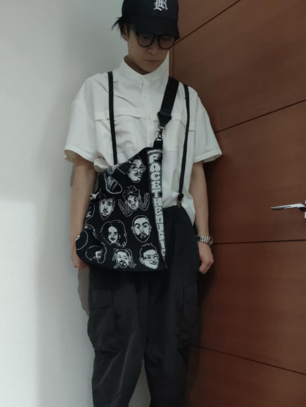 ホワイト系のスニーカー、ブラック系のカーゴパンツを着用したメンズの夏コーディネートの2枚目の写真