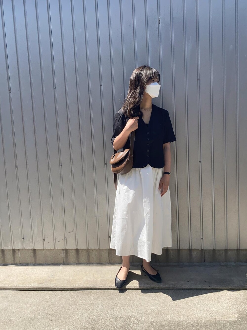 ブラック系のパンプス、ブラック系のシャツ/ブラウス、ホワイト系のスカートを着用したレディースの春コーディネートの2枚目の写真