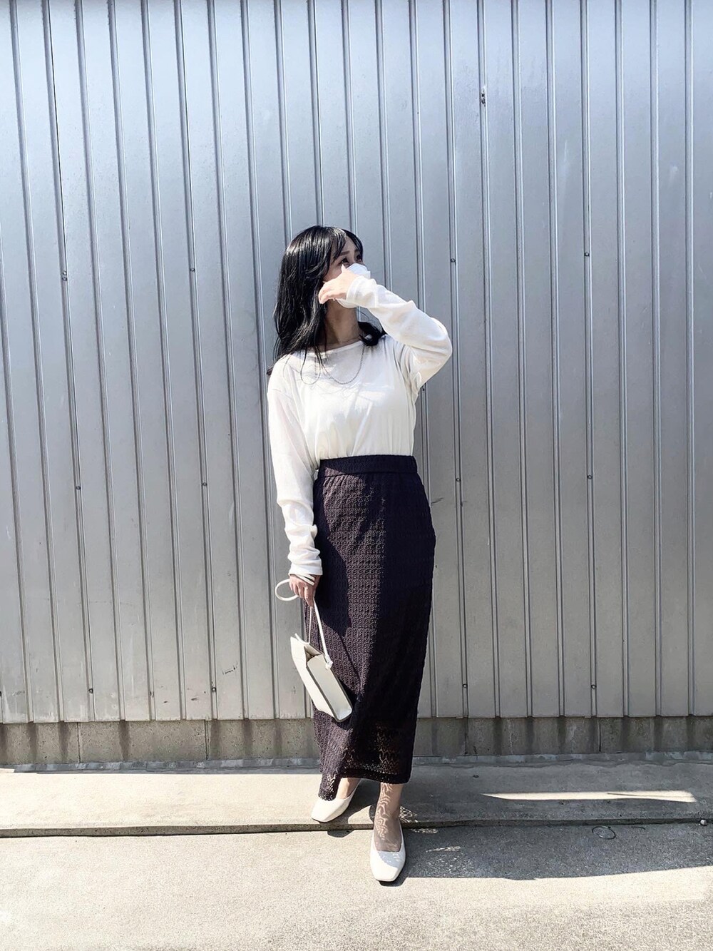 ホワイト系のTシャツ/カットソー、ブラック系のスカート、ホワイト系のサンダルを着用したレディースの春コーディネートの2枚目の写真