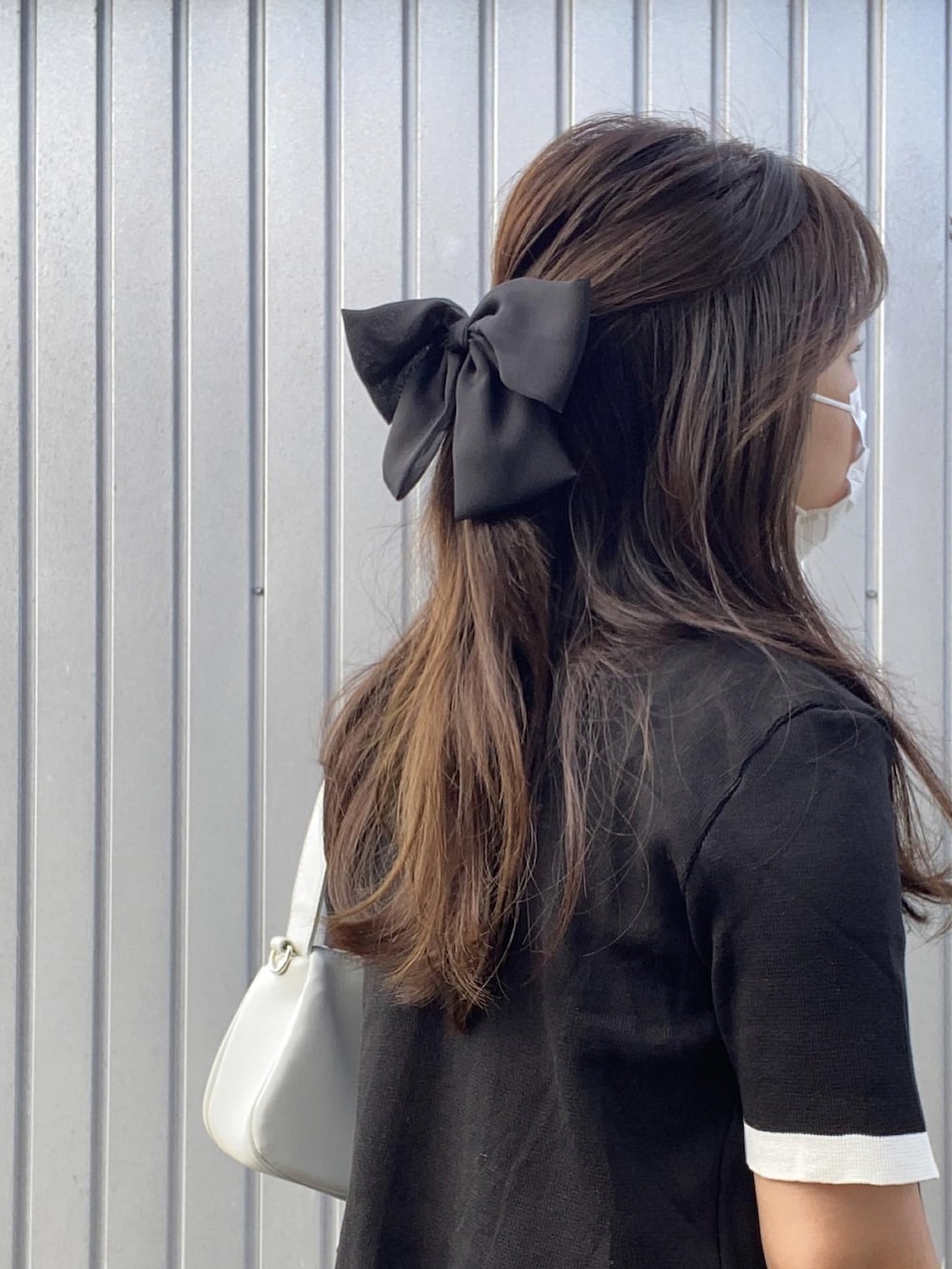 ホワイト系のハンドバッグ、ブラック系のスラックス、ホワイト系のスニーカーを着用したレディースの夏コーディネートの2枚目の写真