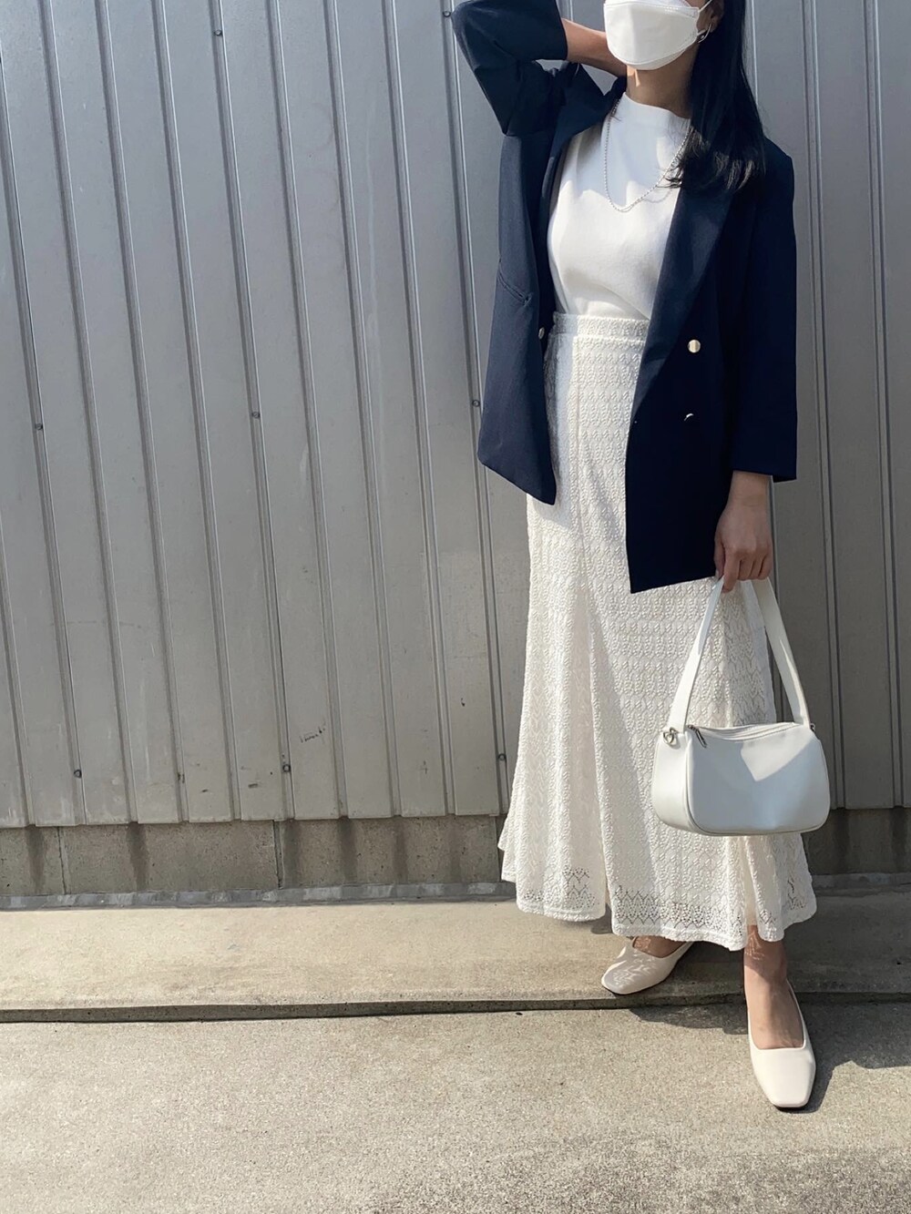 ブルー系のテーラードジャケット、ホワイト系のスカート、ホワイト系のサンダルを着用したレディースの春コーディネートの2枚目の写真