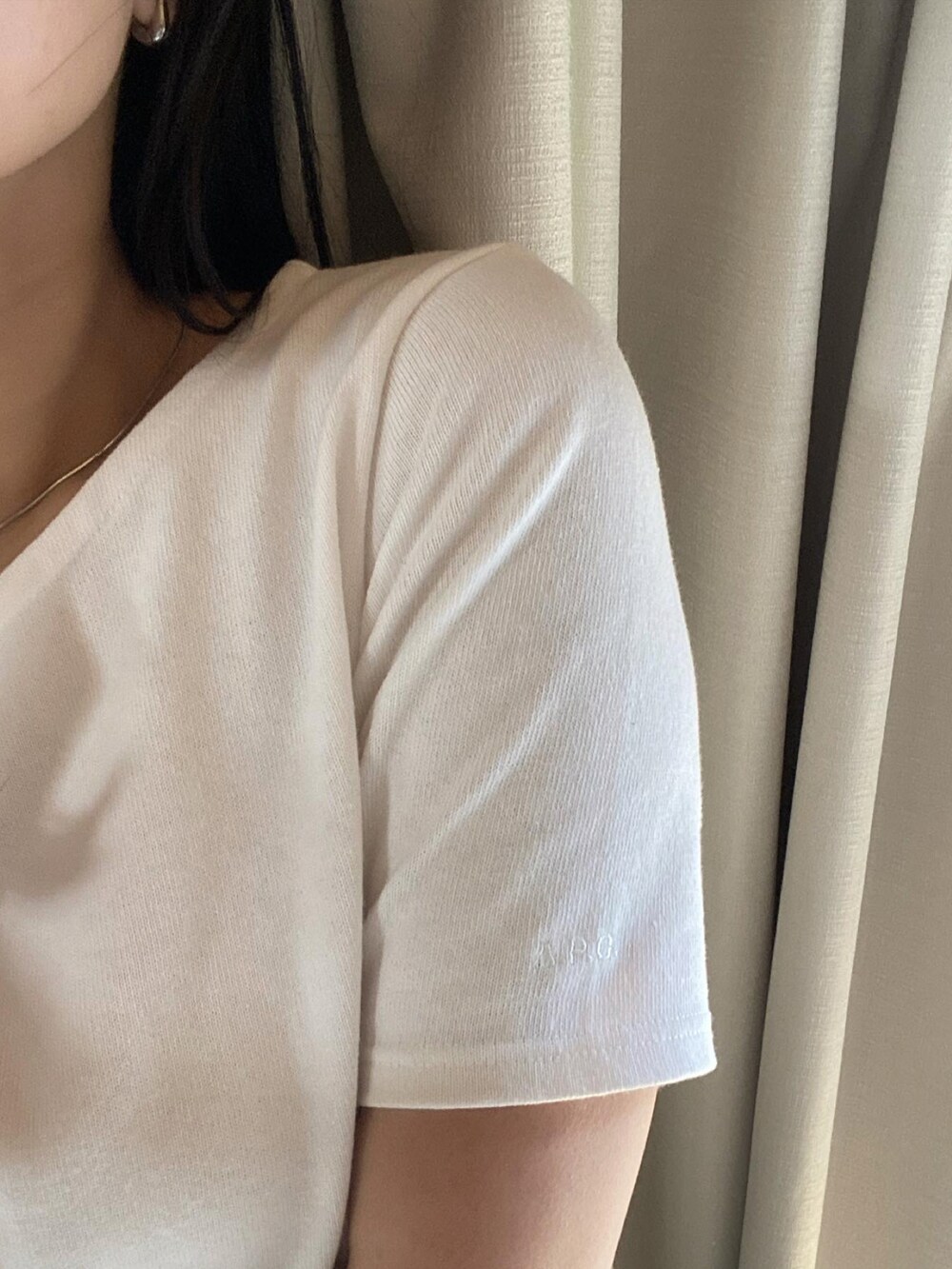 ホワイト系のTシャツ/カットソー、ブラック系のハンドバッグ、グレー系のスラックスを着用したレディースの春コーディネートの2枚目の写真