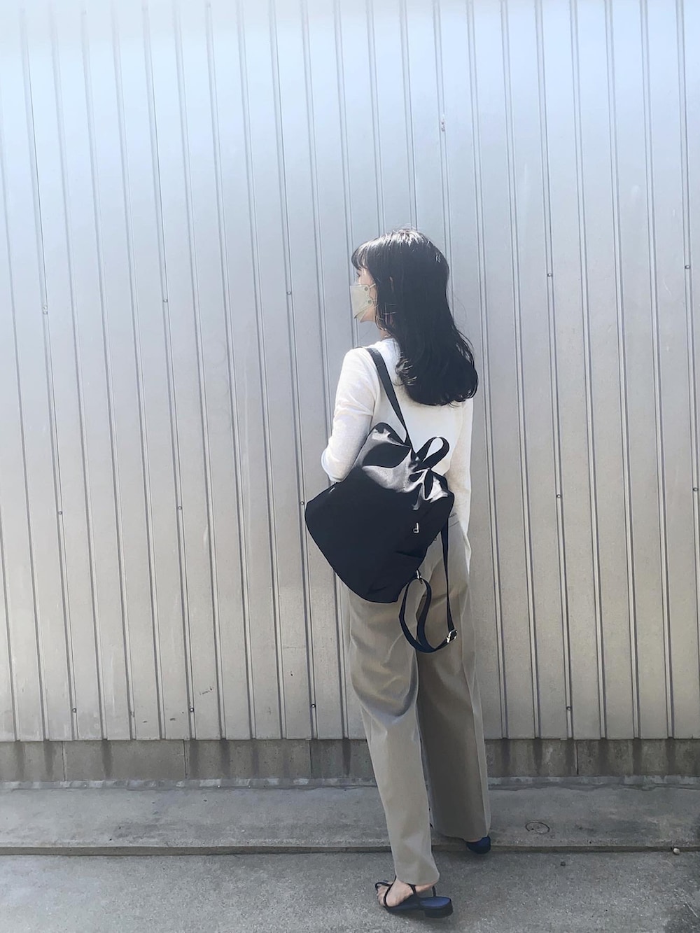 ホワイト系のTシャツ/カットソー、ブラック系のバックパック/リュック、グレー系のスラックスを着用したレディースの春コーディネートの2枚目の写真