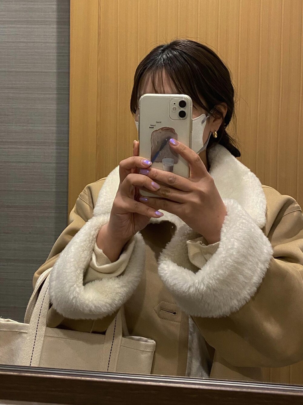 ホワイト系のトートバッグ、ブルー系のデニムパンツ、ベージュ系のムートンコートを着用したレディースの冬コーディネートの2枚目の写真