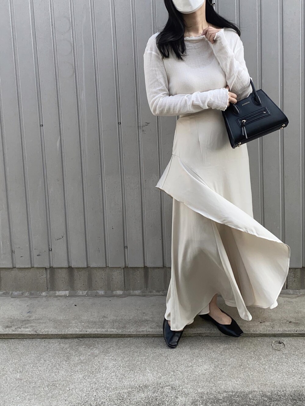ホワイト系のスカート、ブラック系のショルダーバッグ、ブラック系のパンプスを着用したレディースの春コーディネートの3枚目の写真