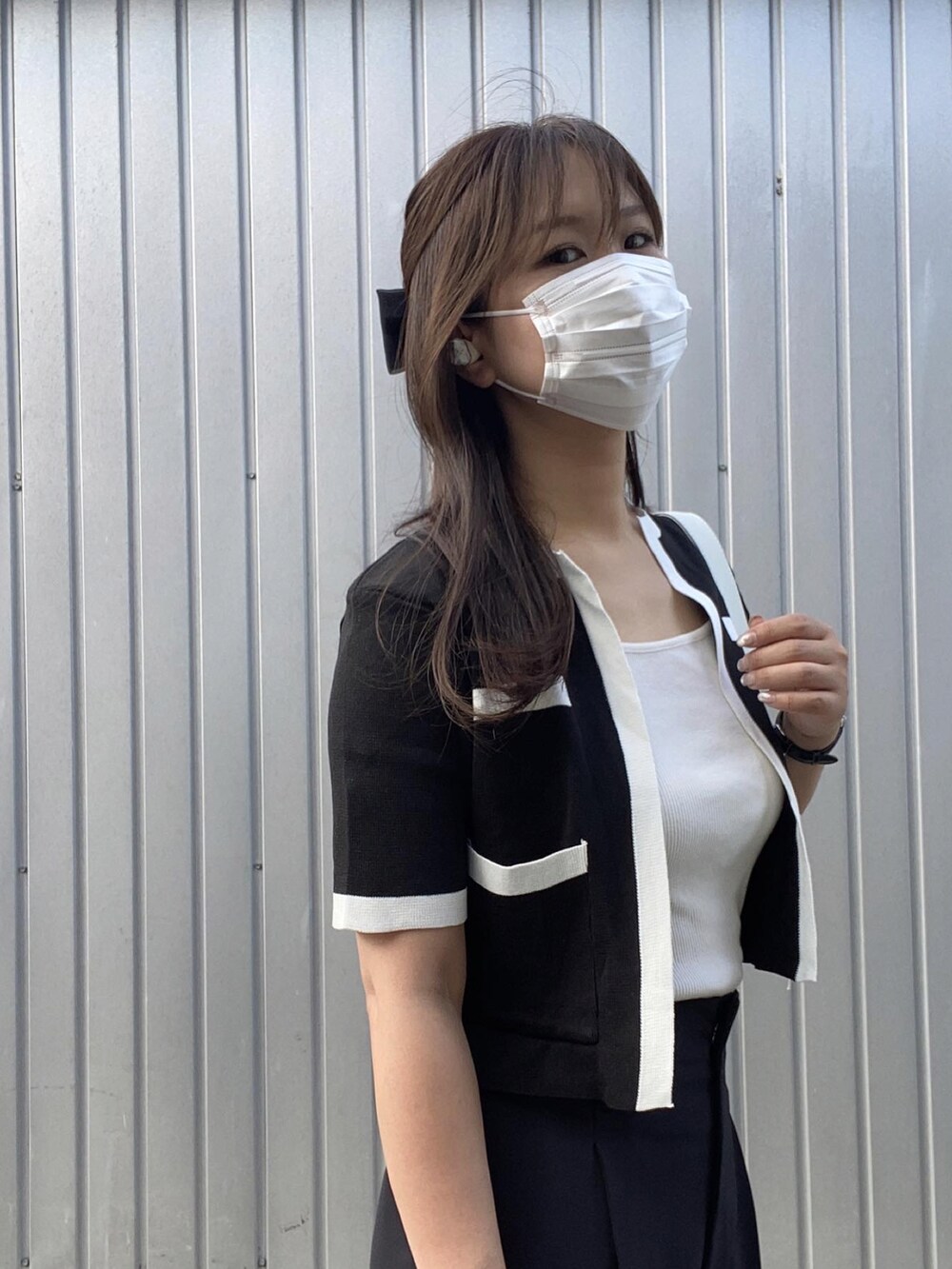 ホワイト系のハンドバッグ、ブラック系のスラックス、ホワイト系のスニーカーを着用したレディースの夏コーディネートの3枚目の写真