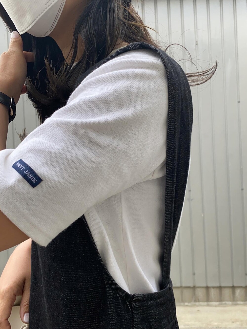 ホワイト系のTシャツ/カットソー、ホワイト系のショルダーバッグ、ブラック系のジャンパースカートを着用したレディースの春コーディネートの4枚目の写真