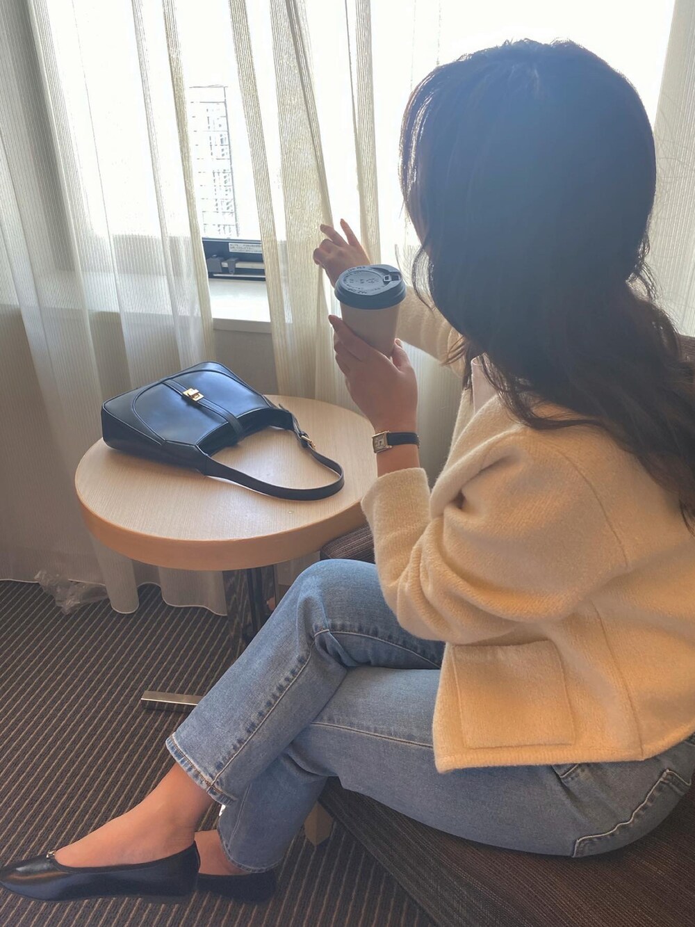 ホワイト系のノーカラーコート、ブルー系のデニムパンツを着用したレディースの春コーディネートの2枚目の写真