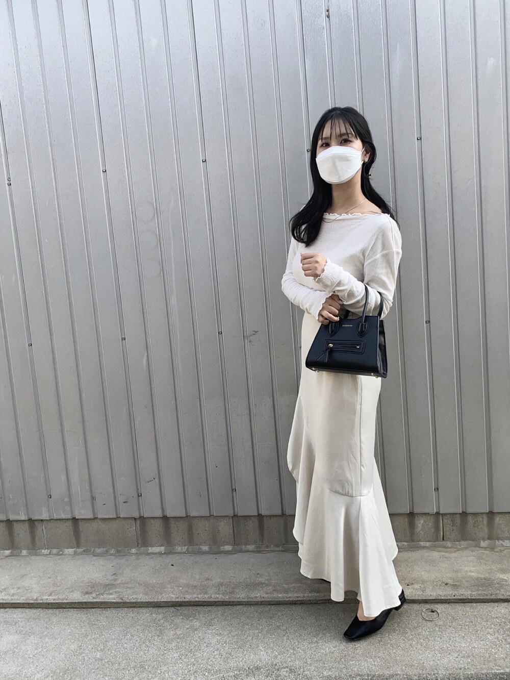 ホワイト系のスカート、ブラック系のショルダーバッグ、ブラック系のパンプスを着用したレディースの春コーディネートの2枚目の写真