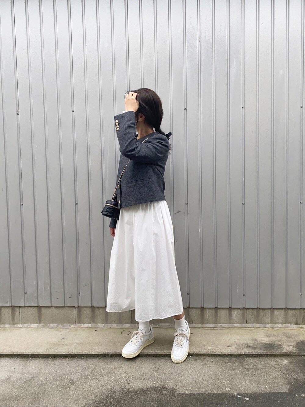 グレー系のノーカラージャケット、ブラック系のショルダーバッグ、ホワイト系のスカートを着用したレディースの秋コーディネートの2枚目の写真