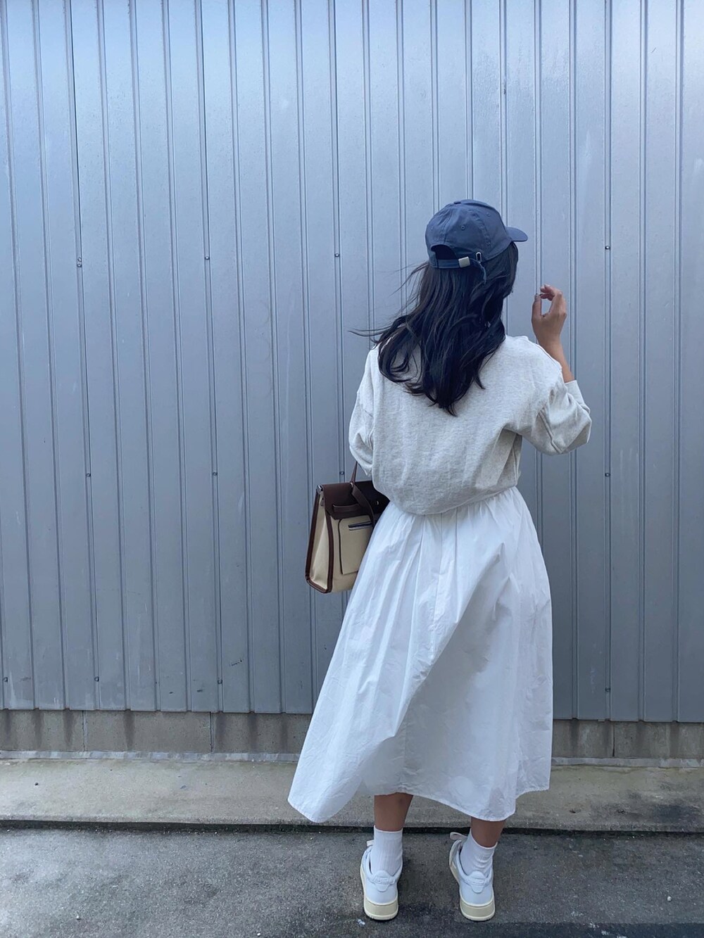 ホワイト系のスニーカー、ホワイト系のスカート、ブルー系のキャップを着用したレディースの秋コーディネートの2枚目の写真