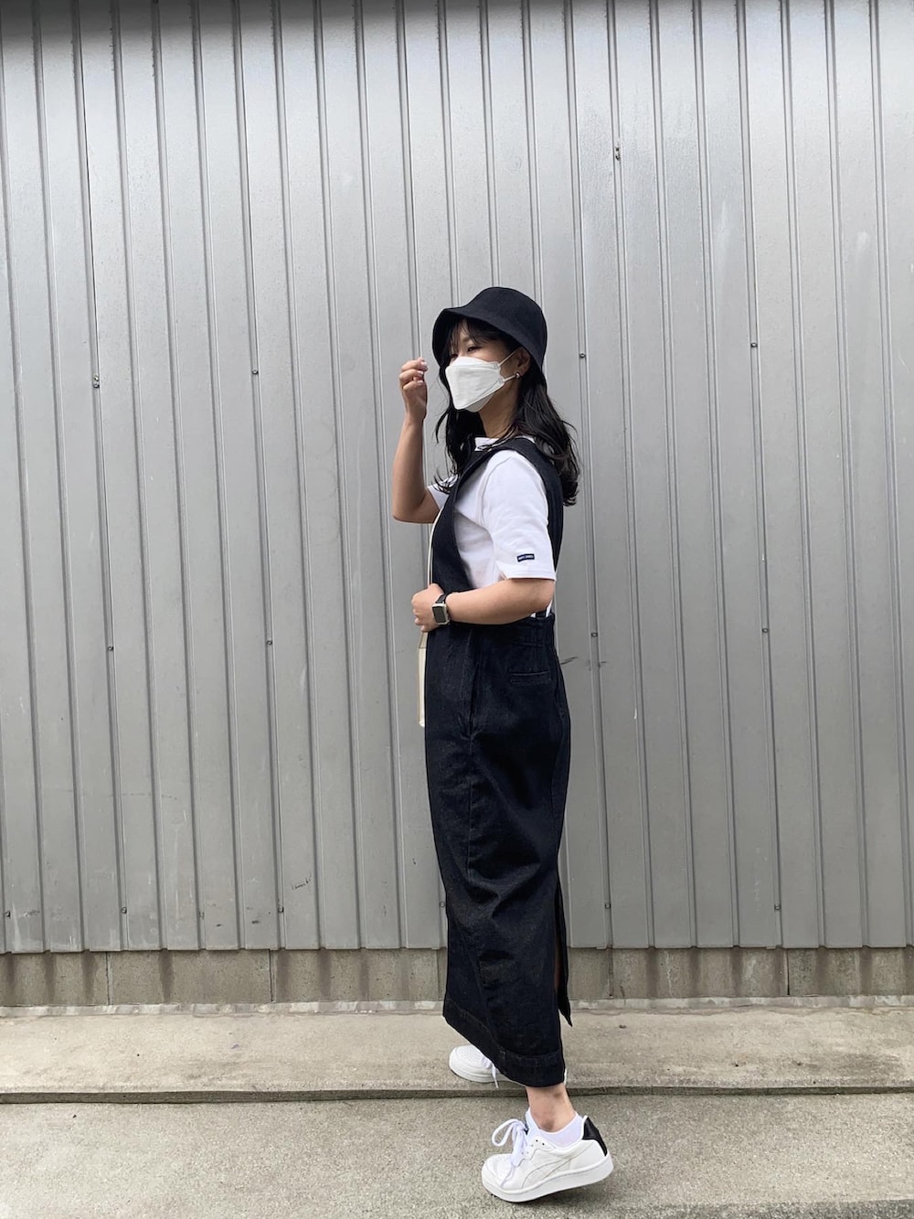 ホワイト系のTシャツ/カットソー、ホワイト系のショルダーバッグ、ブラック系のジャンパースカートを着用したレディースの春コーディネートの2枚目の写真