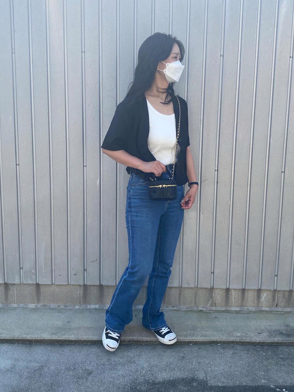 ブラック系のシャツ/ブラウス、ブラック系のショルダーバッグ、ブルー系のデニムパンツを着用したレディースの秋コーディネートの2枚目の写真