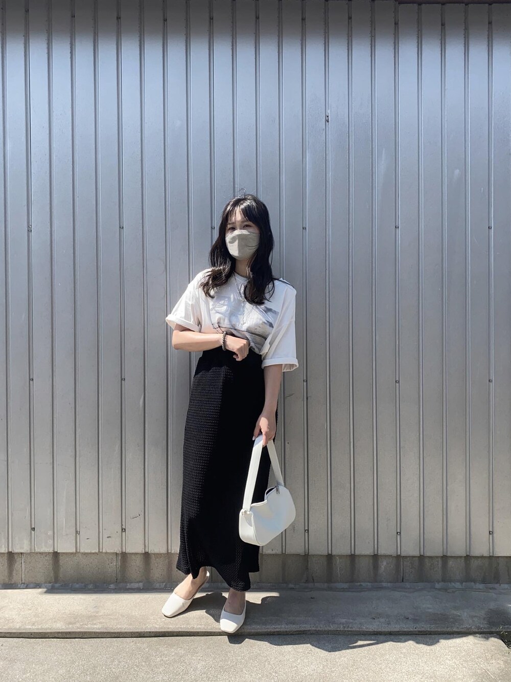 ホワイト系のTシャツ/カットソー、ブラック系のスカート、ホワイト系のサンダルを着用したレディースの春コーディネートの2枚目の写真